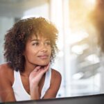 Female looking in mirror and touching her face skin