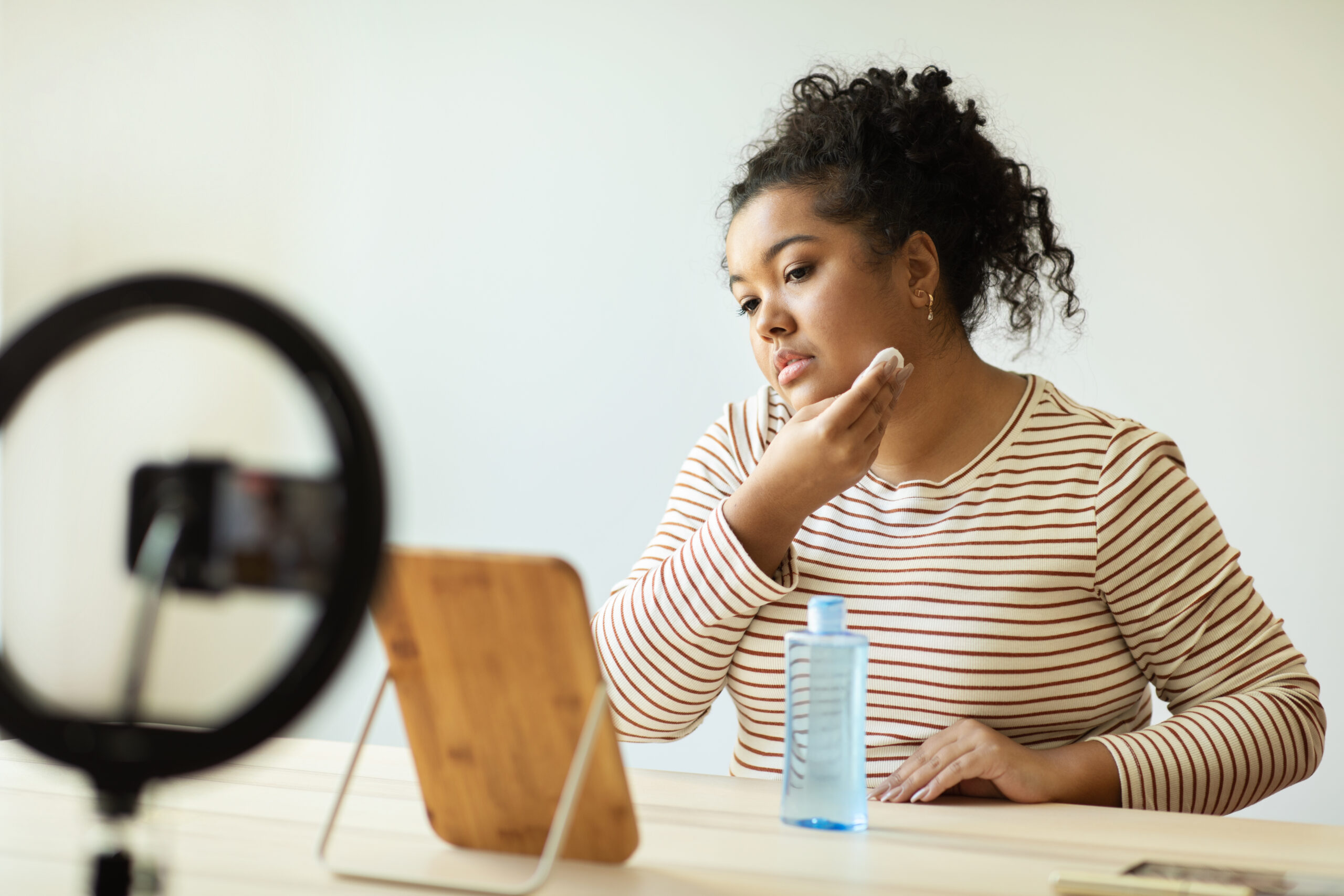 Woman applying makeup in front of a mirror.