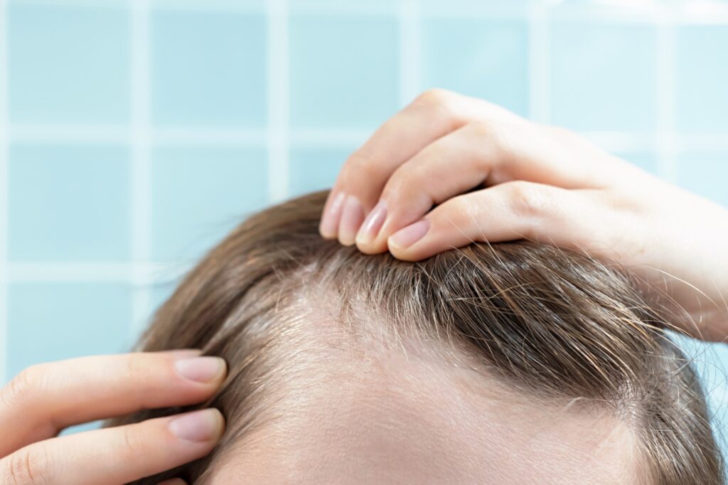 Girl touching her hair close-up on blue background, hair loss concept.